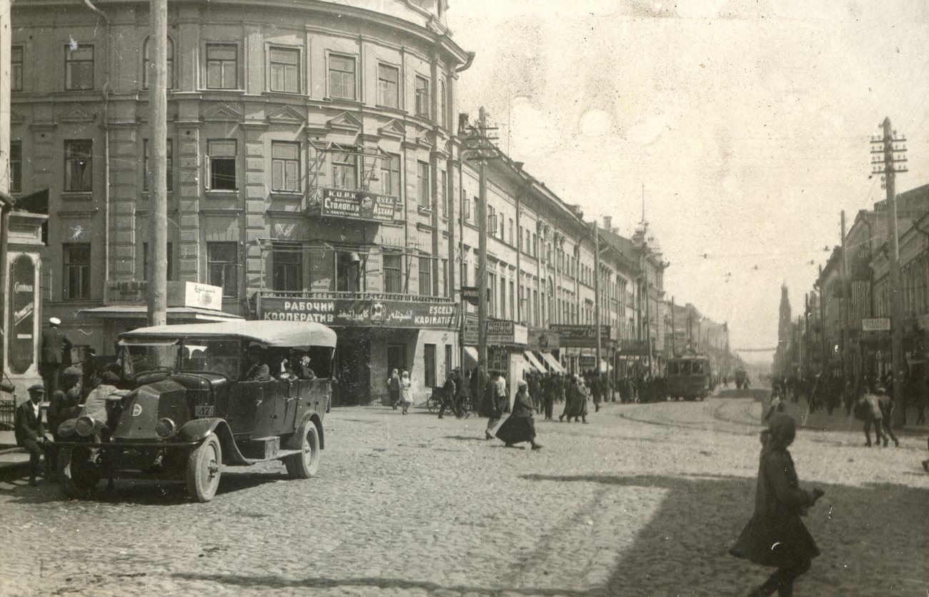 An open-topped bus at a corner of Bauman Street in Kazan in 1929, as people cross the cobbles and a tram comes up the street