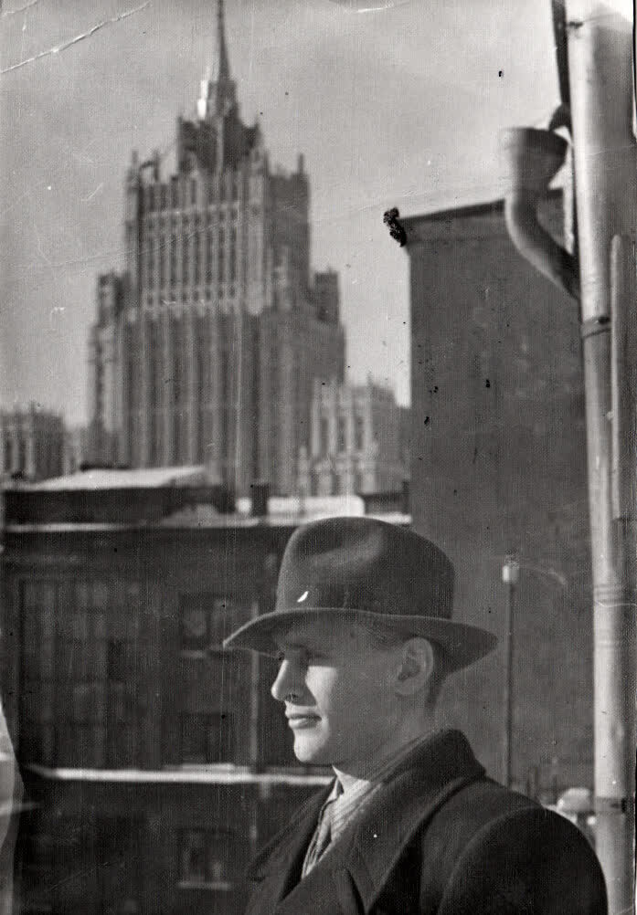 A man in a hat on a balcony at 43 Arbat Street in Moscow in 1951, a Stalin-era tower rising behind him
