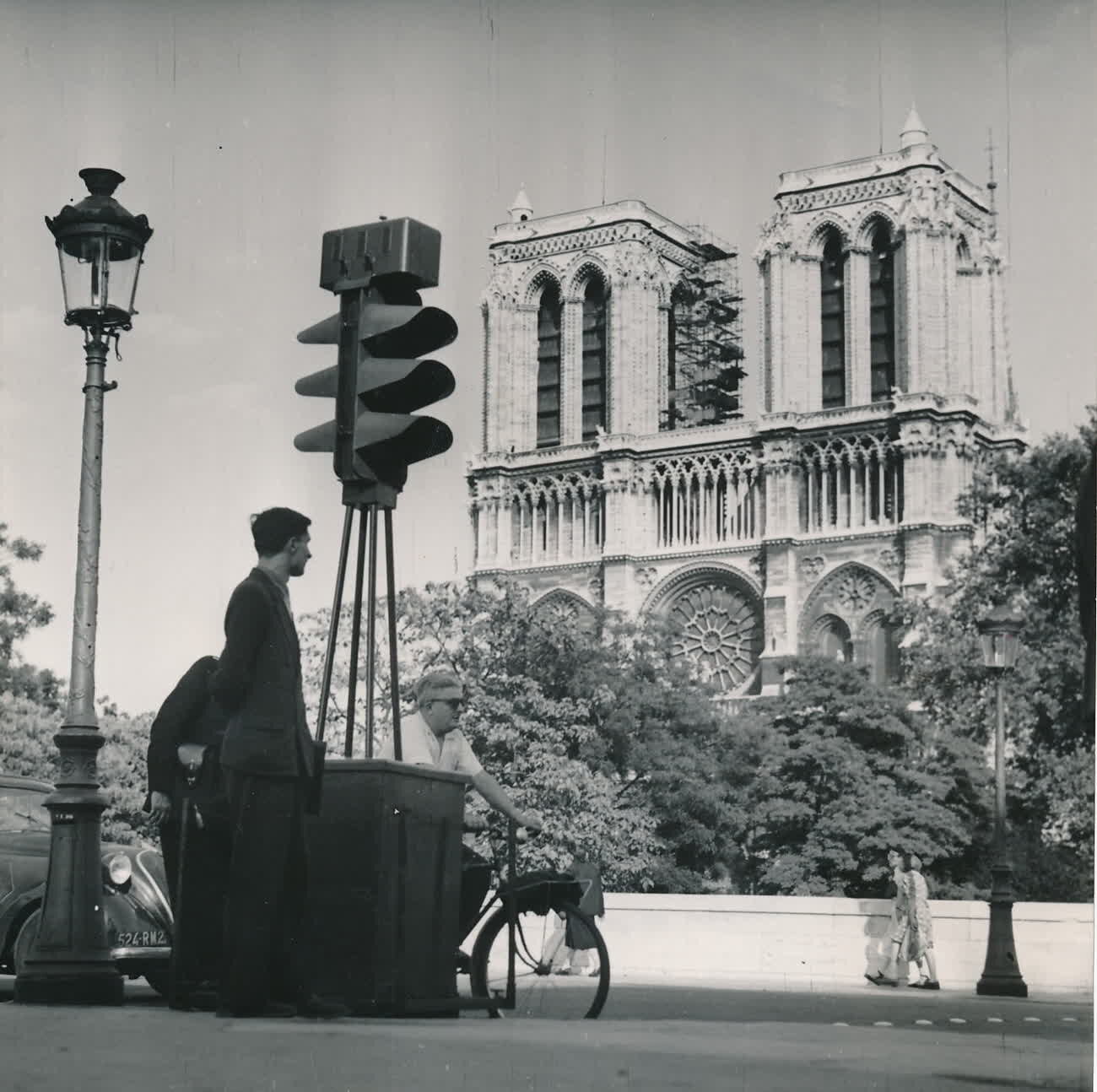 A man standing by traffic lights in front of Notre-Dame in Paris in 1950