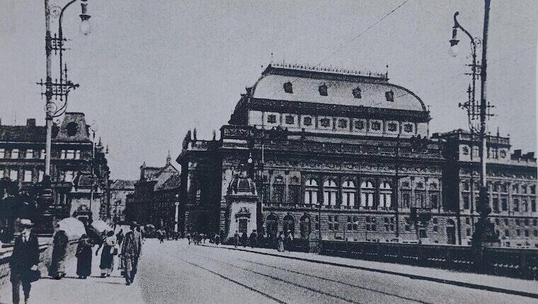 The National Theatre in Prague in 1909, with people walking on the embankment