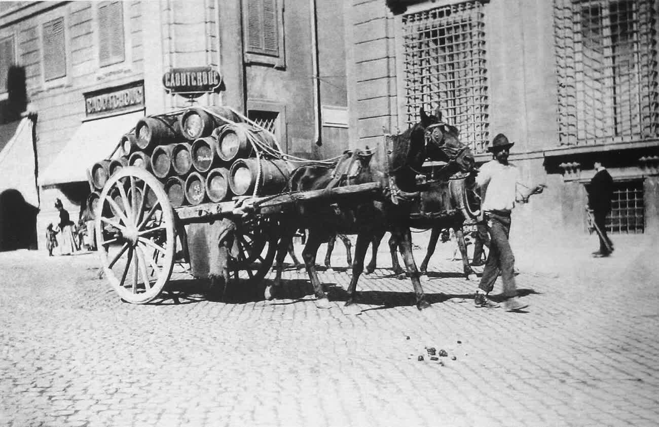 A horse-drawn cart loaded with wine barrels crossing Piazza Venezia in Rome in 1900