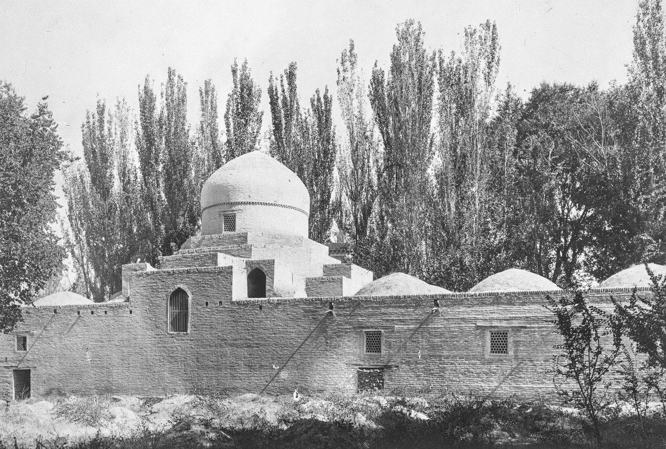 The domed brick Namazgokh Mosque in Tashkent behind its long outer wall, framed by tall poplars, in the early 1900s