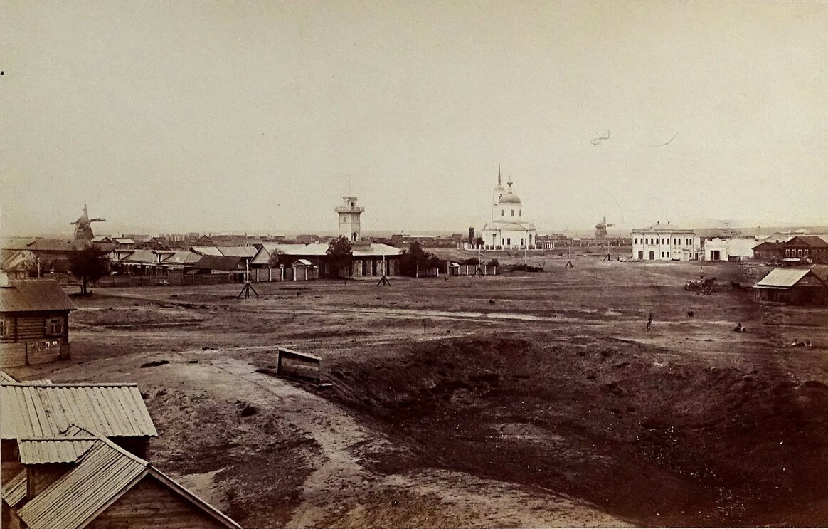 The wide, unpaved Town Square of Tsaritsyn, today Volgograd, in 1875, with a lookout tower, a white church and windmills on the flat skyline