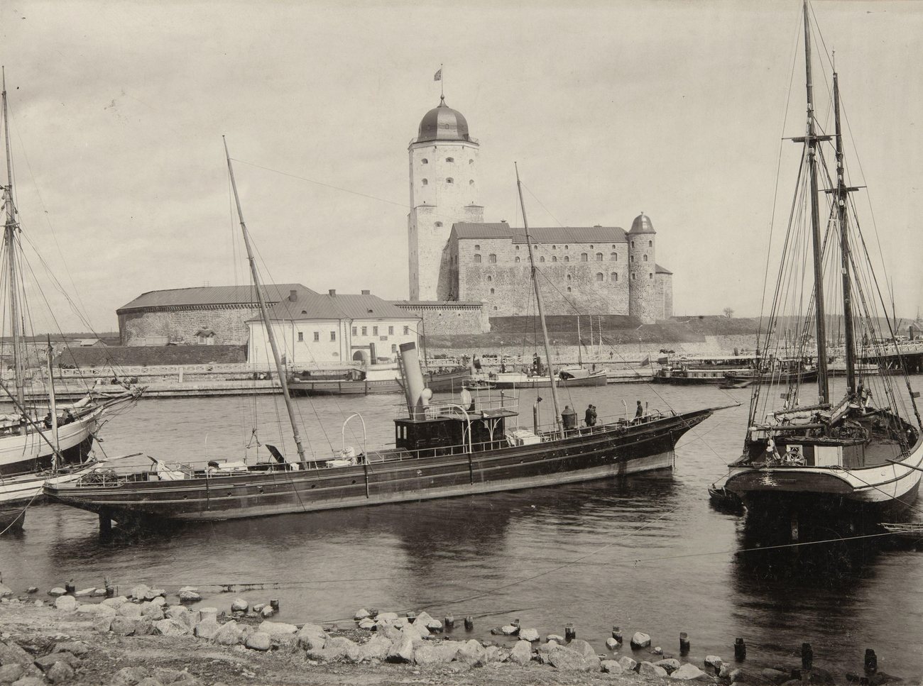 A steam yacht and sailing ships moored in the harbour below Vyborg Castle and the domed St Olaf's Tower, between 1895 and 1900