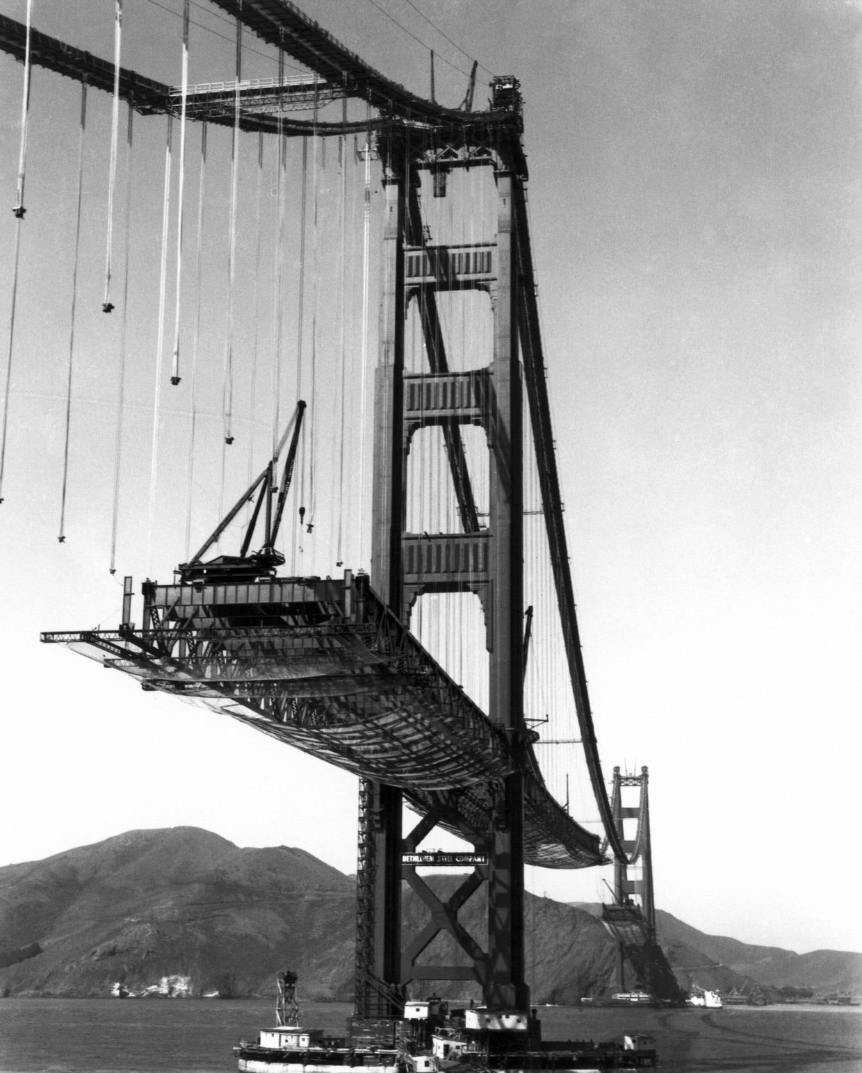 The Golden Gate Bridge under construction in 1936, the roadway hanging half-finished from the south tower