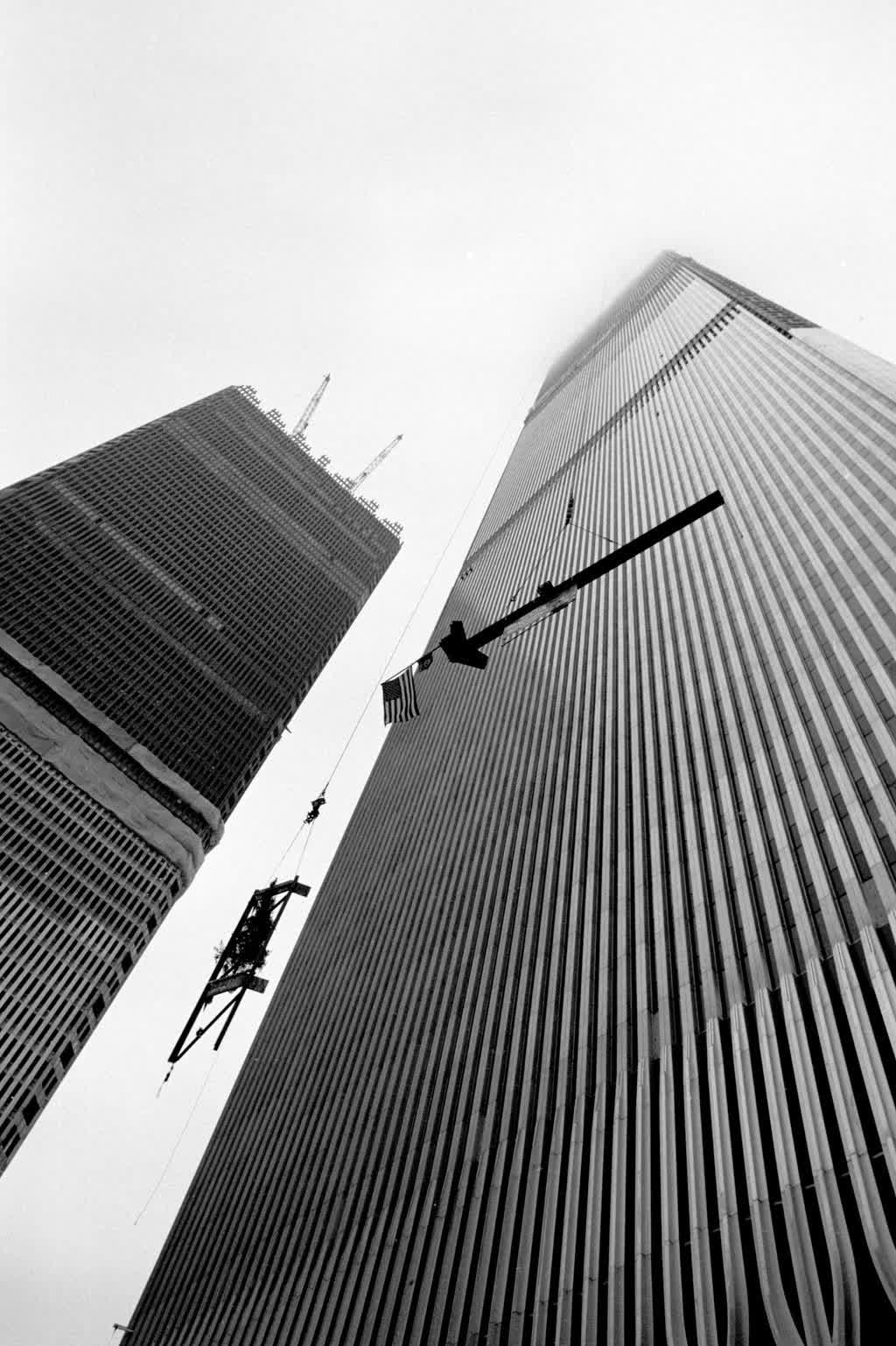 The Twin Towers of the World Trade Center under construction in 1970, seen from below with a crane and workers